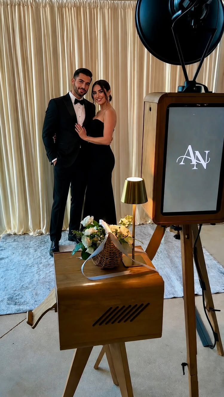 13 Wedding Reception Ideas for Guests Who Love Fun 2 Couple posing in front of a vintage wooden photo booth with cream curtains.