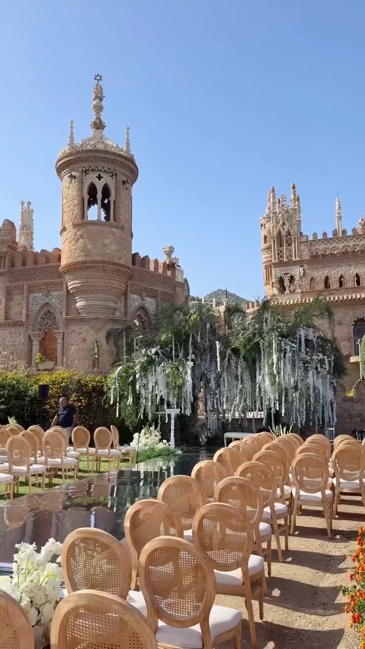 17 Wedding Reception Venues for Every Style and Budget 13 Wedding ceremony seating with cane chairs in front of an ornate stone castle.