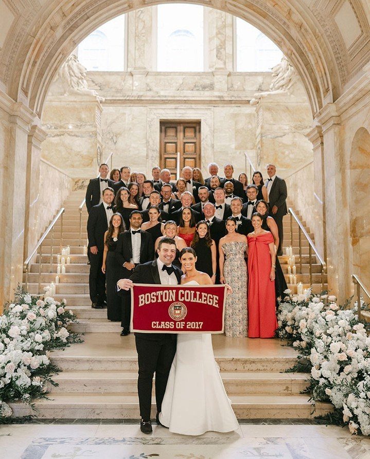 17 Wedding Reception Venues for Every Style and Budget 9 Wedding party posing on marble stairs holding a Boston College alumni banner.