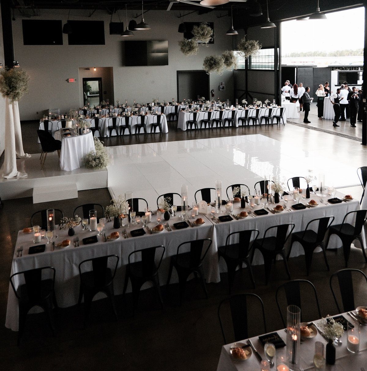 17 Wedding Reception Venues for Every Style and Budget 7 Industrial warehouse wedding reception with long white tables, black chairs, and white dance floor.