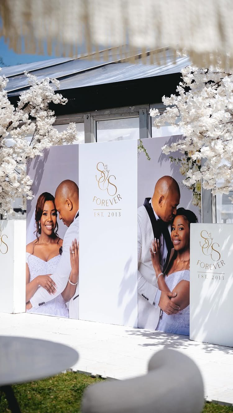 Wedding backdrop with large photos of a couple and white cherry blossom flowers.