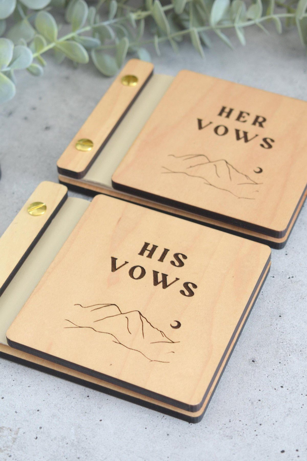 Wooden vow books engraved with His Vows and Her Vows and mountain scenery.