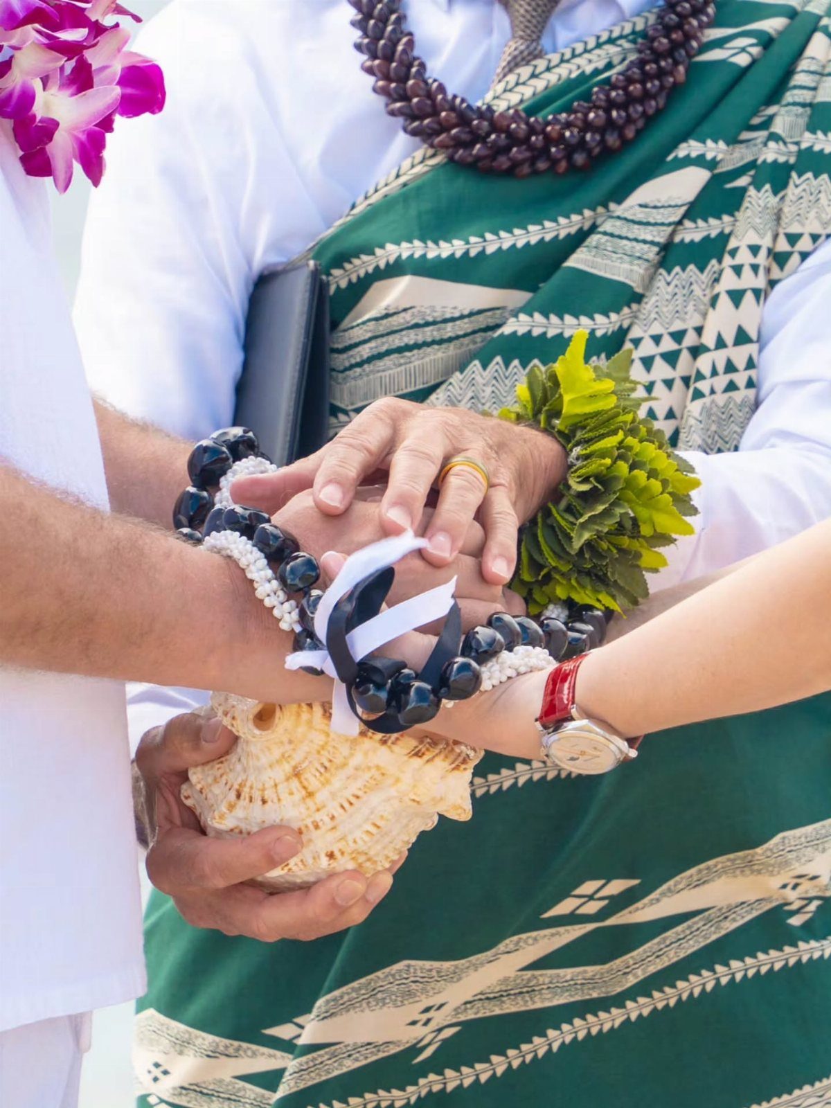 Hands of a couple holding a seashell during a traditional wedding renewal ceremony.
