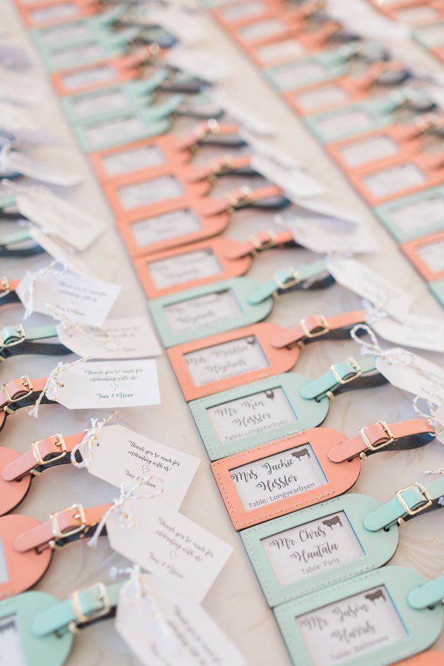 Luggage tag place cards in peach and mint green for a travel theme wedding.