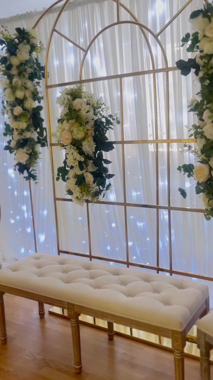 7 Wedding Stage Decorations for Romantic Receptions 6 Gold geometric metal backdrop with white flowers and a tufted white bench.