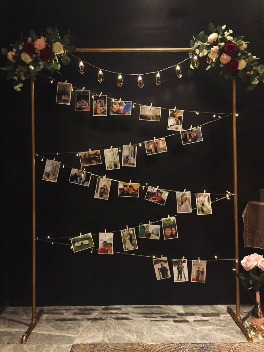 10 Wedding Venue Decorations for a Standout Celebration 10 Gold frame with string lights and clipped photographs against a black wall.