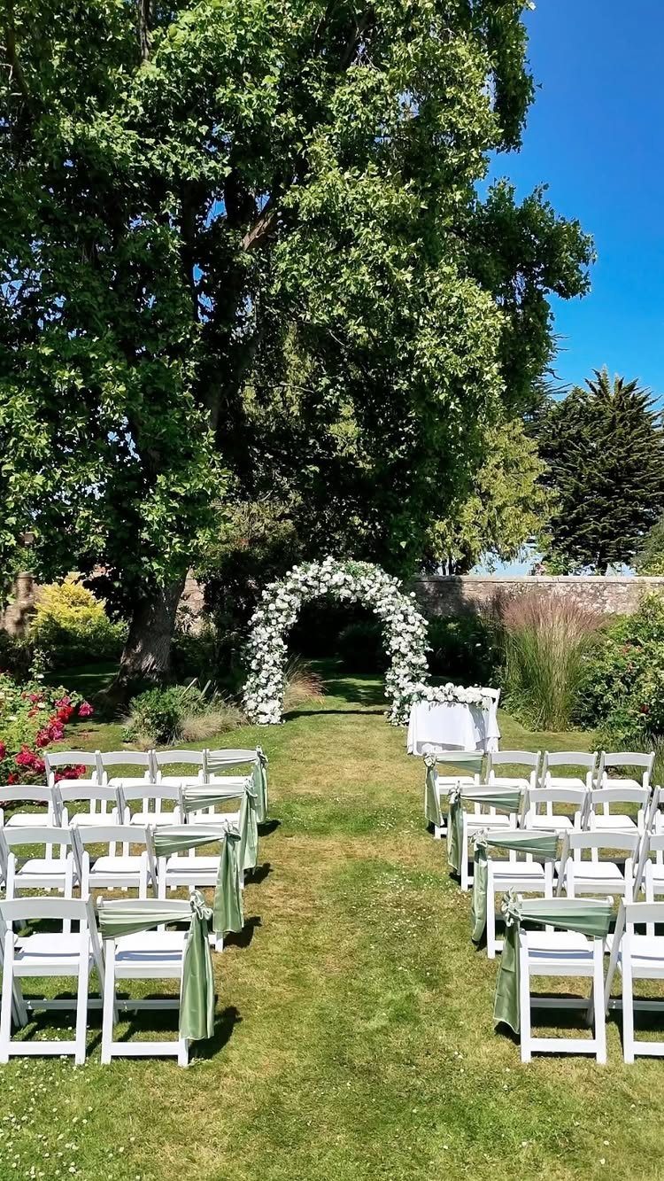 Wedding Venues Western Couples Love: 16 Ideas 5 Outdoor wedding ceremony setup with white chairs and a floral arch under a tree.