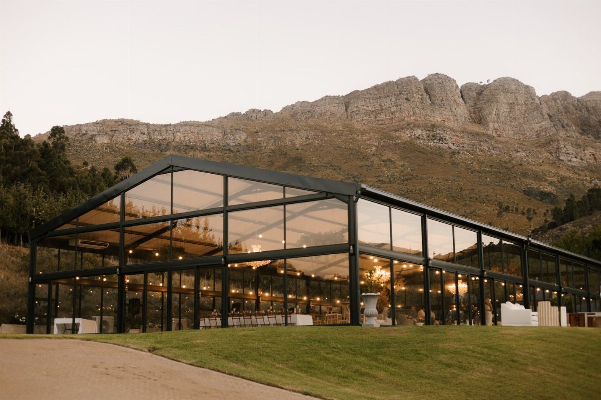 Wedding Venues Western Couples Love: 16 Ideas 13 Modern glass pavilion wedding venue set against a backdrop of rocky mountains.