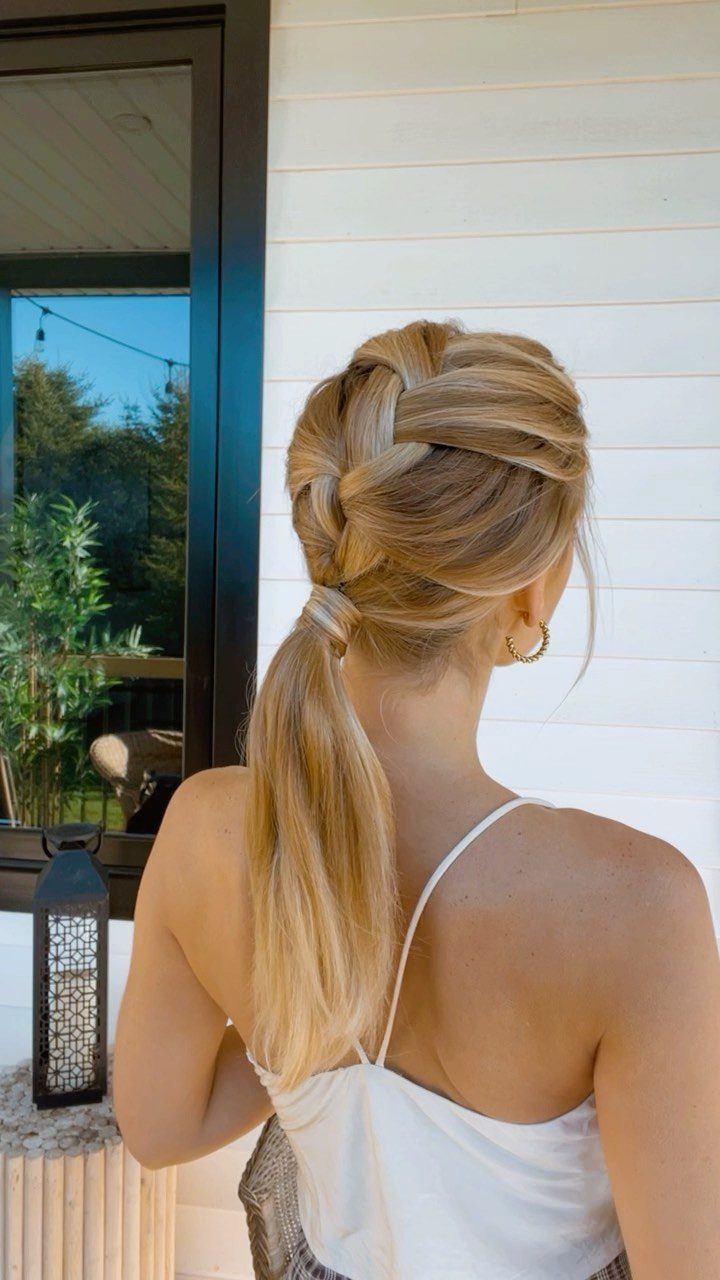 Blonde woman with a thick braid leading into a low ponytail from behind.