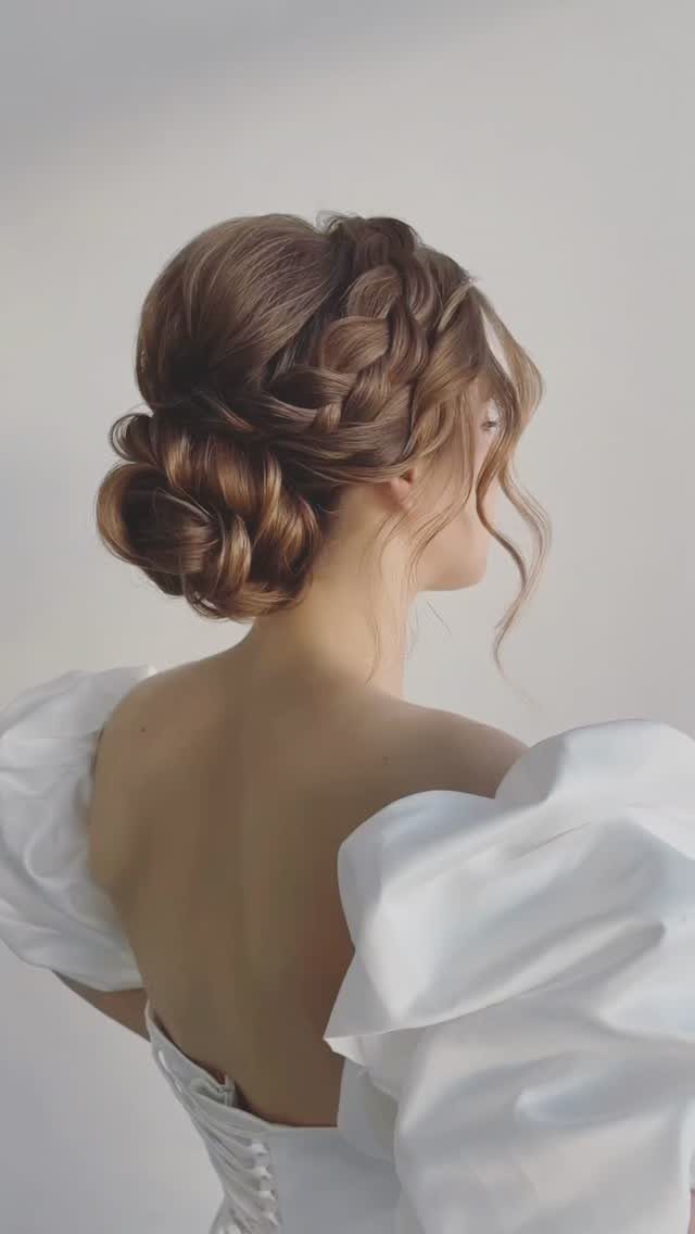 Woman with an intricate braided updo wearing a white puff-sleeved wedding dress.