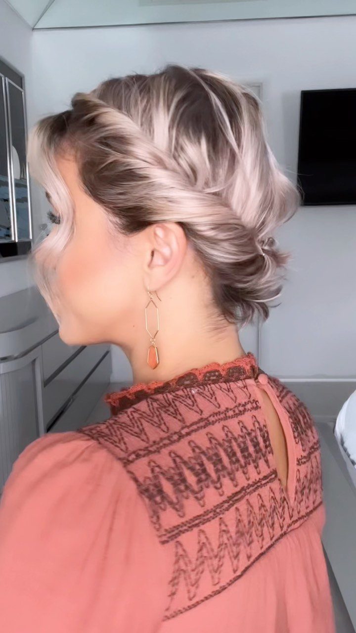 Woman with blonde hair in a textured low updo wearing a peach blouse.